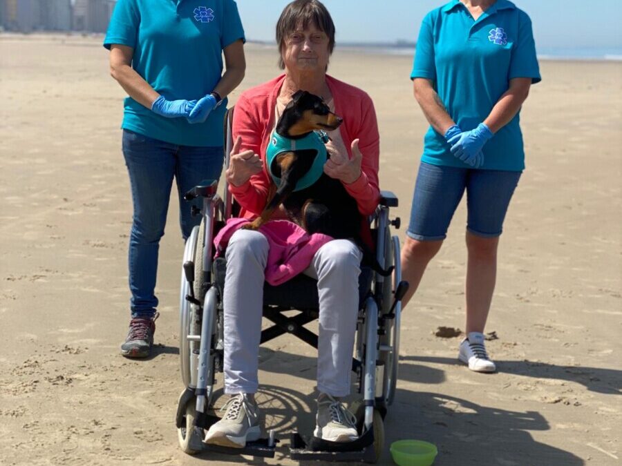 Wensambulance met mevrouw op strand met haar hondje